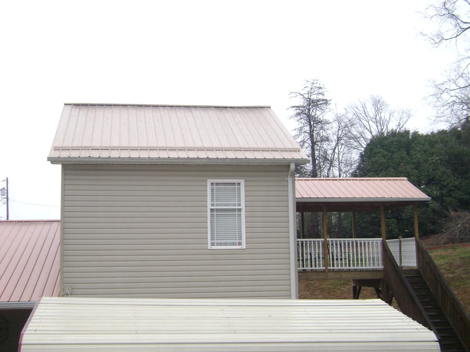 Tan metal roofs on a two story addition and attached porch, from a Roof Replacement job in Boiling Springs